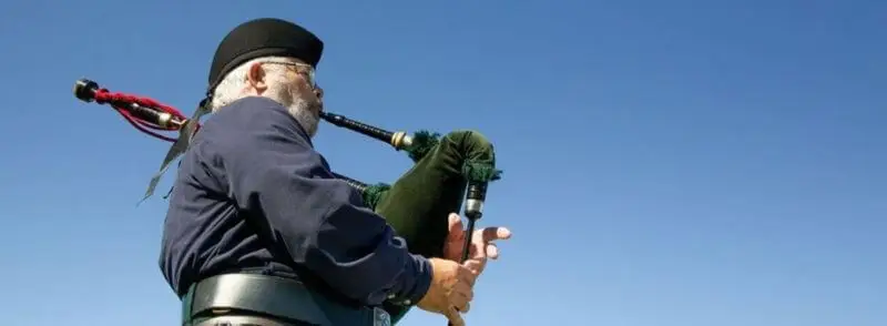 Gaitero escocés tocando música tradicional escocesa con una gaita