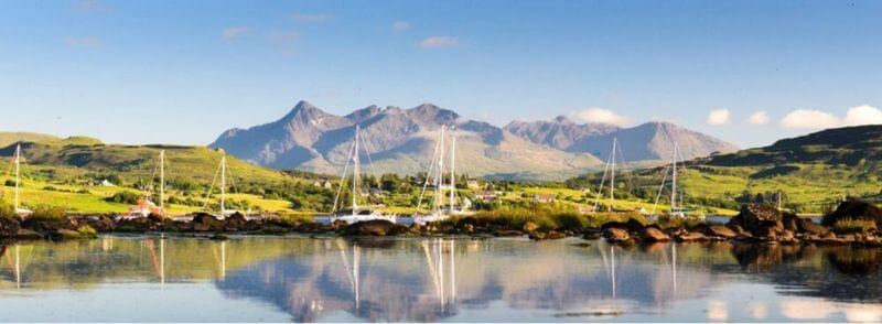 Vista de la bahía de Portree con las montañas Cuillin al fondo, en la Isla de Sky, Escocia