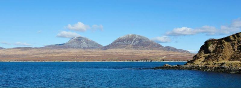Paisaje de la Isla de Jura con el mar y las montañas al fondo en Escocia
